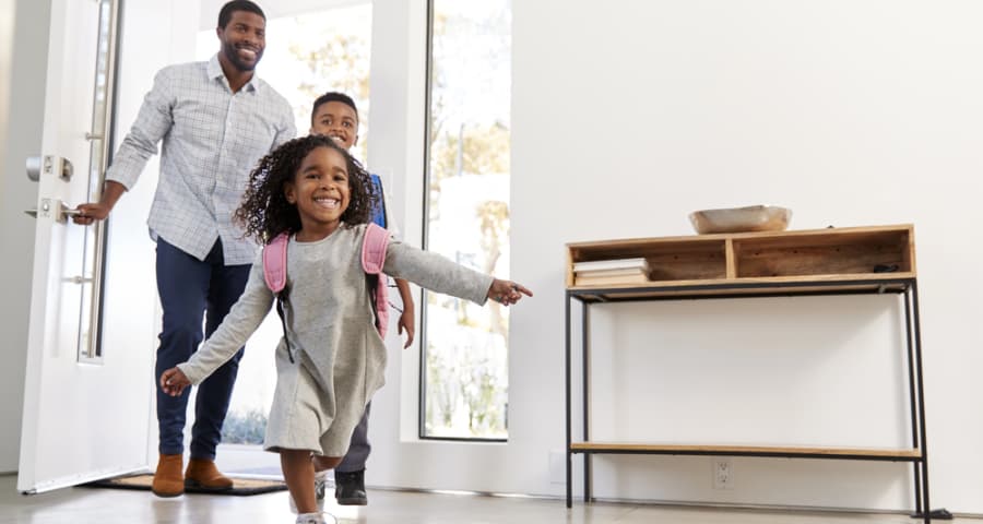 Father and children walking through the front door of their home