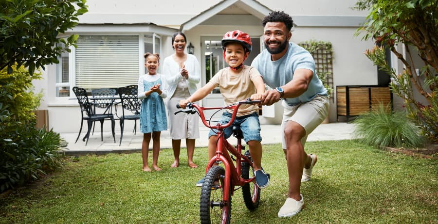 Boy learning to ride a bike at home with family